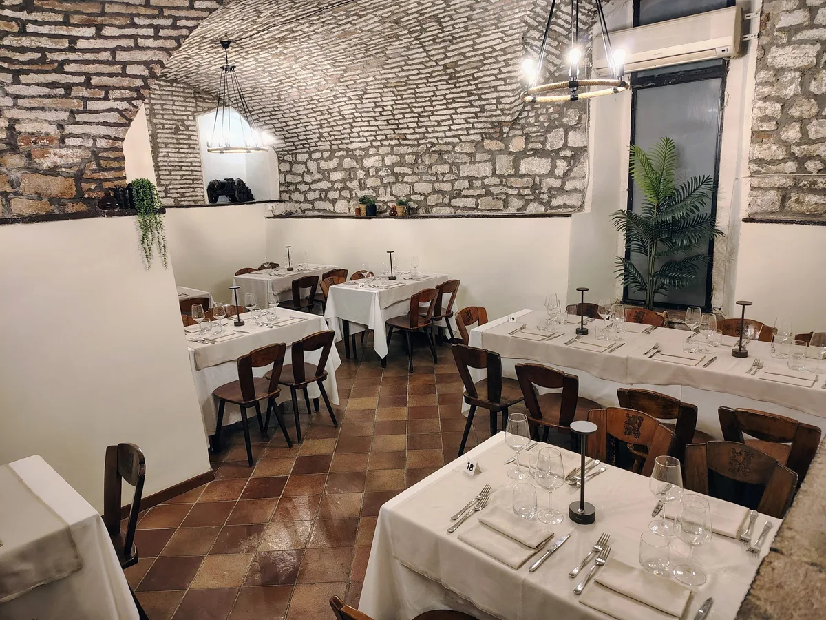 Sala interna della Grotta dei Priori — volte in pietra e tavoli apparecchiati con candele