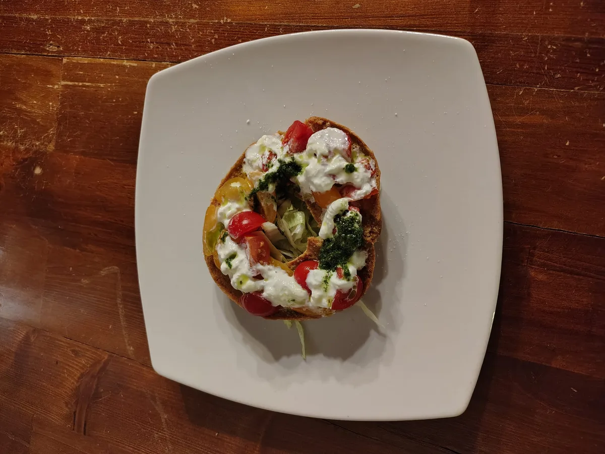 Frisella con mozzarella, pomodorini e pesto di basilico su piatto bianco