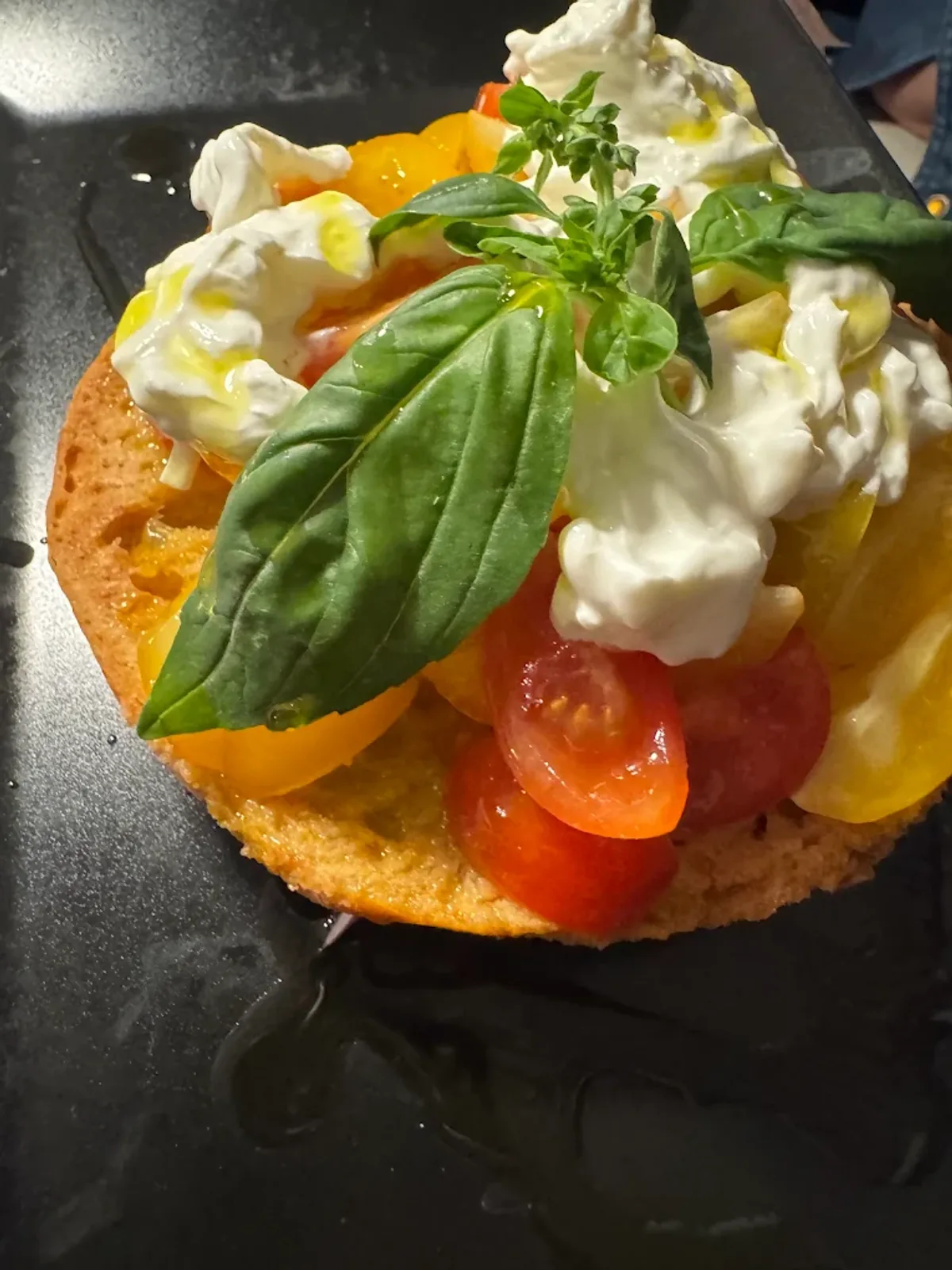Frisella con burrata cremosa, pomodorini gialli e rossi e foglie di basilico fresco