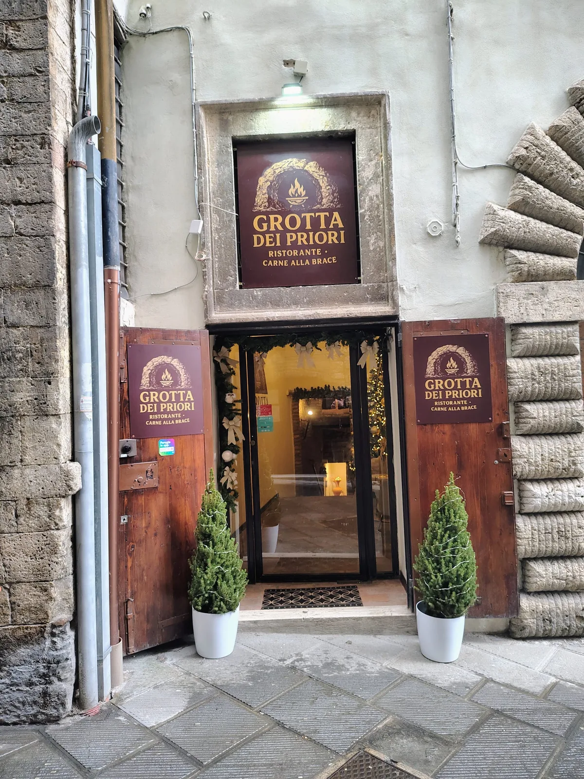 Ingresso della Grotta dei Priori in Via dei Priori, Perugia — insegna dorata su fondo bordeaux