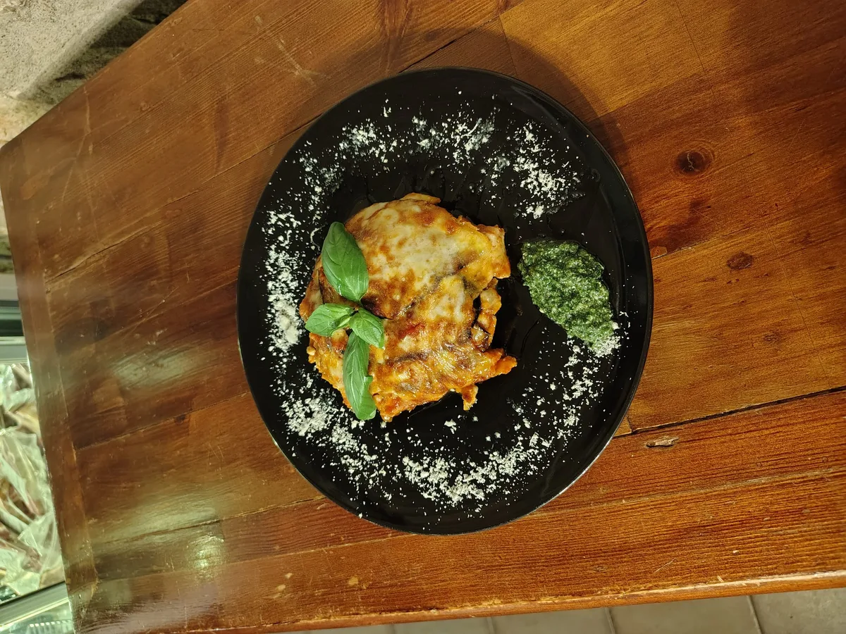 Lasagna al forno con basilico fresco e parmigiano su piatto nero
