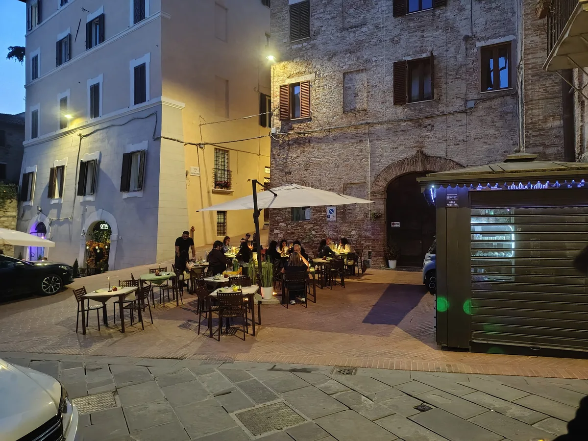 Piazza della Grotta dei Priori al tramonto — atmosfera blue hour con tavoli illuminati