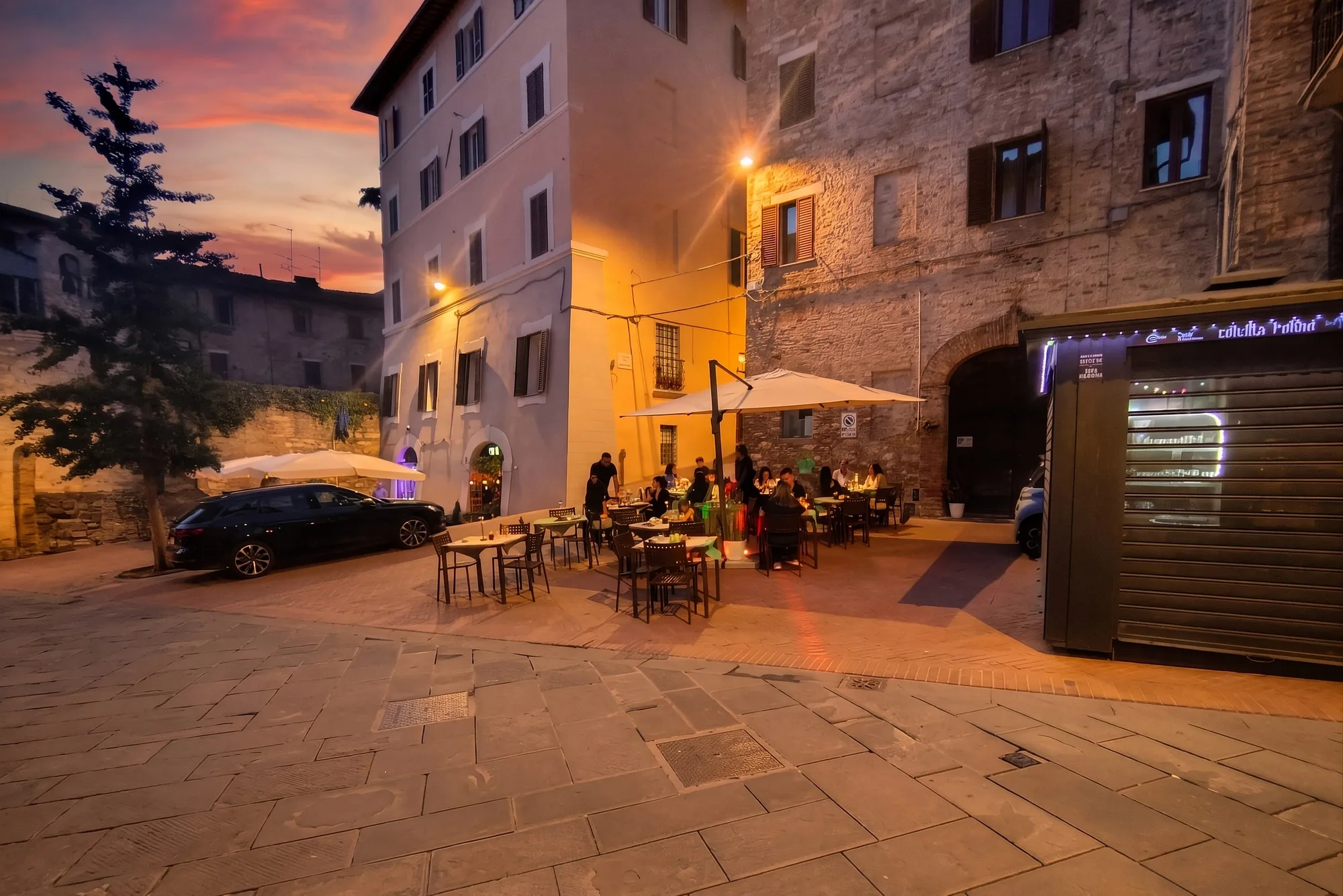 La piazza di Via dei Priori al tramonto, con i tavoli all'aperto tra le mura storiche di Perugia